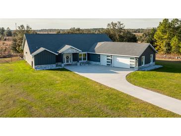 Single-story home with gray siding, stone accents, and a three-car garage at 18459 Sw 66Th Loop, Dunnellon, FL 34432