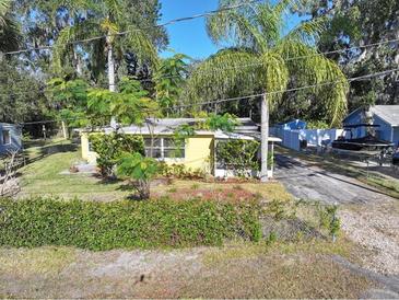 Aerial view of a charming yellow house with a lush green lawn and palm trees at 1975 Lake Dr, New Smyrna Beach, FL 32168