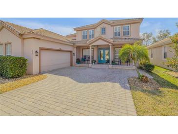 Charming two-story home showcasing a paved driveway, two-car garage, and manicured landscaping at 454 Venetian Villa Dr, New Smyrna Beach, FL 32168