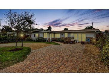 Charming single-story home with a brick driveway, manicured lawn, and well-lit exterior at 4650 Saxon Dr, New Smyrna Beach, FL 32169