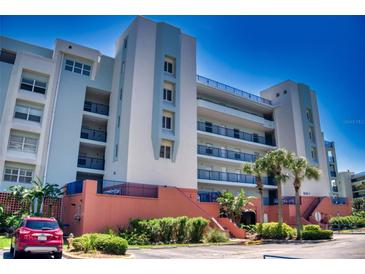 Multi-story building featuring multiple balconies and a manicured landscape with palm trees on a bright, sunny day at 5300 S Atlantic Ave # 3-504, New Smyrna Beach, FL 32169