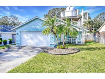 Light teal house with a white garage door, palm trees, and a spiral staircase at 806 E 21St Ave, New Smyrna Beach, FL 32169