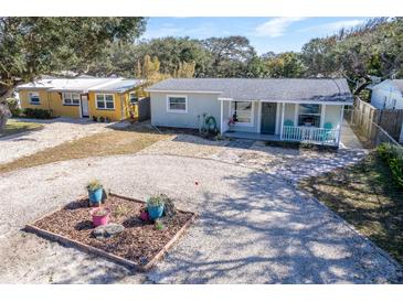 Charming home featuring a gravel driveway and inviting front porch with cheerful blue seating at 817 E 12Th Ave, New Smyrna Beach, FL 32169