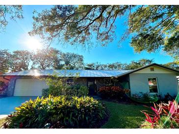 Ranch-style home with metal roof, landscaping, and a two-car garage at 832 S Cooper St, New Smyrna Beach, FL 32169