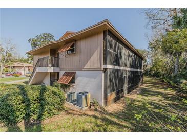 Side view of the condo with a screened in patio and steps leading to the front door, showing AC units at 150 Wax Myrtle Woods Ct # 7B, Deltona, FL 32725
