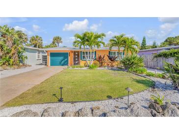 Charming home with a well-manicured front lawn, complemented by lush landscaping and vibrant tropical plants at 308 Normandy Ave, New Smyrna Beach, FL 32169