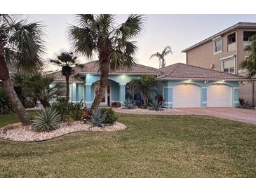 Charming blue single-story home with a two-car garage, tile roof, and lush tropical landscaping at 3728 Egret Dunes Dr, Ormond Beach, FL 32176