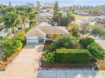 Charming single-story home featuring a well-manicured lawn, mature landscaping, and a concrete driveway at 601 N Peninsula Ave, New Smyrna Beach, FL 32169