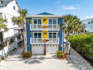Coastal home featuring palm trees, white railings, surfboards and a three-car garage in a beach community at 6531 Turtlemound Rd, New Smyrna Beach, FL 32169