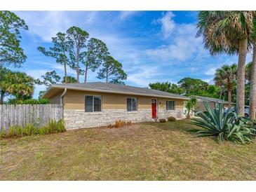 Charming single-story home with a brick facade, red door, and partially fenced yard at 1043 Beulah Dr, Edgewater, FL 32132