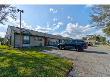 View of a tan siding townhouse with black car parked in front under a cloudy blue sky at 1140 Fairvilla Dr, New Smyrna Beach, FL 32168