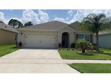 Charming single-story home featuring an attached two-car garage, tropical landscaping, and a well-manicured lawn at 123 Old Mill Pond Rd, Edgewater, FL 32141