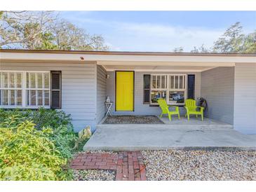 Inviting front entrance with a bright yellow door and chairs, complemented by lovely landscaping at 128 Dixwood Ave, Edgewater, FL 32132