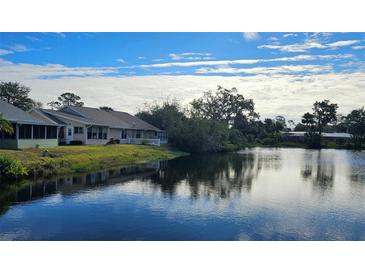 Scenic view of the home backed by a serene pond under a partly cloudy sky at 26 Birdie Dr, New Smyrna Beach, FL 32168