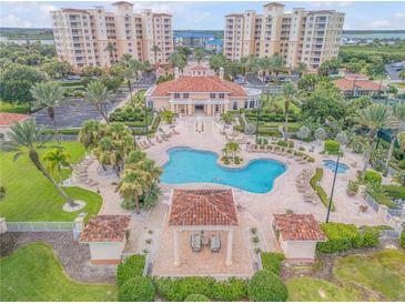 Aerial view of a community pool with lush landscaping and tile roof cabanas, surrounded by resort-style condo buildings at 263 Minorca Beach Way # 801, New Smyrna Beach, FL 32169