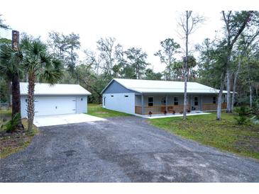 Charming single-story home featuring a detached garage and long gravel driveway at 2995 Ragis Rd, Edgewater, FL 32132