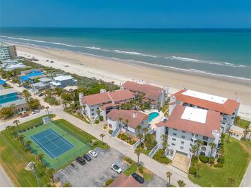 Expansive aerial view of beachfront condos featuring a pool, tennis court, and private beach access at 3001 S Atlantic Ave # 204, New Smyrna Beach, FL 32169