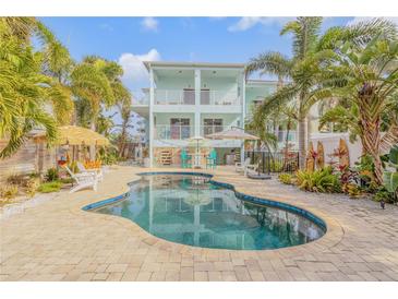 An inviting outdoor pool surrounded by lush tropical landscaping and a charming home at 604 S Atlantic Ave, New Smyrna Beach, FL 32169