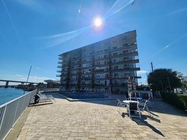 Exterior view of the condominium complex with a pool and outdoor seating area, all set against a blue sky at 101 N Riverside Dr # 2090, New Smyrna Beach, FL 32168