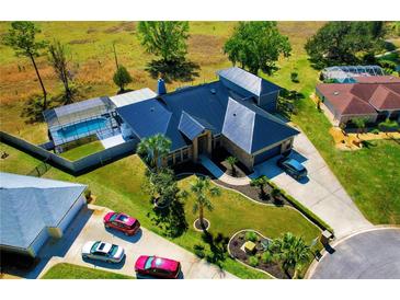 Stunning aerial view of home featuring lush landscaping, a spacious driveway, and screened in pool at 1948 Spruce Creek Lndg, Port Orange, FL 32128