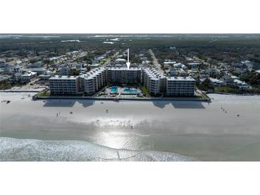 Stunning aerial view of beachfront condo building with pool, sandy beach, and lush landscaping at 2401 S Atlantic Ave # A604, New Smyrna Beach, FL 32169