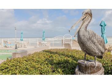 Pelican statue overlooking outdoor lounge area with tables, chairs, and umbrellas at 2401 S Atlantic Ave # D301, New Smyrna Beach, FL 32169