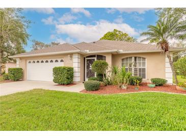 Charming single story home with lush landscaping, a well-manicured lawn, and attached two car garage at 2626 Turnbull Estates Dr, New Smyrna Beach, FL 32168