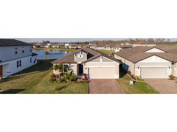 Inviting home with a brick driveway and attached two-car garage, complemented by lush landscaping and a view of the pond at 2820 Neverland Dr, New Smyrna Beach, FL 32168