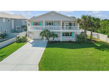 Charming two-story home with double balconies, a well-manicured lawn, and a long concrete driveway at 4624 Van Kleeck Dr, New Smyrna Beach, FL 32169