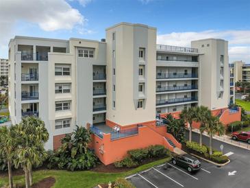 Multi-story condo complex with colorful exterior, lush landscaping and ample parking on a sunny day at 5300 S Atlantic Ave # 3-301, New Smyrna Beach, FL 32169