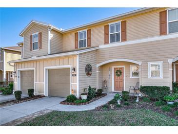 Charming townhome with tan siding, brown shutters, well manicured lawn, and an inviting front entryway at 94 Bella Vita Way, Ormond Beach, FL 32174
