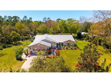 Beautiful single-story home with a metal roof, brick accents and a well-manicured lawn with mature landscaping at 1370 Jane Lacey Ln, New Smyrna Beach, FL 32168
