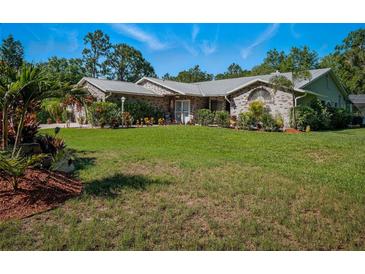Charming single-story brick home featuring a metal roof, manicured lawn and beautifully landscaped flowerbeds at 1370 Jane Lacey Ln, New Smyrna Beach, FL 32168