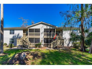 Condo with screened porches and wooden stairs in a grassy area with trees under a clear blue sky at 1600 Big Tree Rd # I2, South Daytona, FL 32119