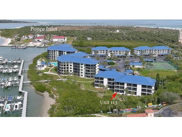 Aerial view of waterfront condos with blue roofs, marina, and ocean view in Ponce Inlet at 2700 N Peninsula Ave # 113, New Smyrna Beach, FL 32169