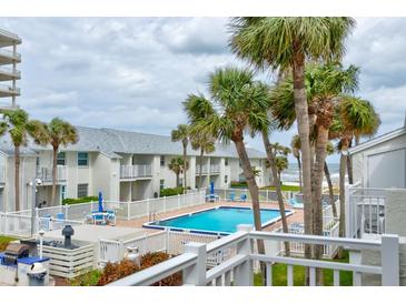 Resort pool area surrounded by palm trees, white fencing and community buildings at 4225 S Atlantic Ave # 2150, New Smyrna Beach, FL 32169