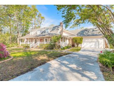 Charming home with a sprawling front porch, large driveway, and well-manicured lawn and mature trees at 1910 Botree Ct, Port Orange, FL 32128