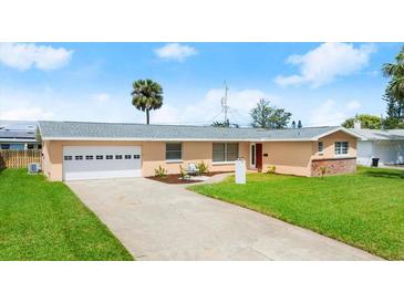 Charming single-story home features a well-maintained lawn, a two-car garage, and a classic concrete driveway at 121 Ellicott Dr, Ormond Beach, FL 32176