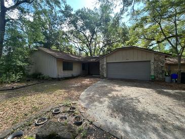 Charming single-story home with stone accents and attached two-car garage nestled among mature trees at 38 Snaresbrook Ct, Ormond Beach, FL 32174
