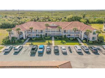 Well maintained condo building featuring a red tile roof, balconies, and parking area at 402 Bouchelle Dr # 206, New Smyrna Beach, FL 32169
