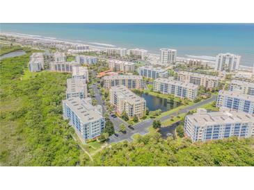 Expansive aerial view of condo community near the beach, with a lake, lush greenery, and ocean views at 5300 S Atlantic Ave # 16-205, New Smyrna Beach, FL 32169