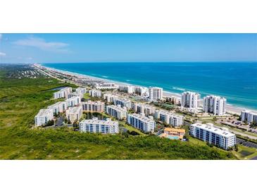 Expansive aerial view of a beachfront condo community with ocean views, lush greenery, and easy beach access at 5300 S Atlantic Ave # 20-507, New Smyrna Beach, FL 32169