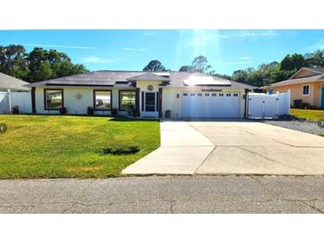 Charming single-story home featuring a well-manicured lawn, solar panels, and an attached two-car garage at 2820 Tamarind Dr, Edgewater, FL 32141
