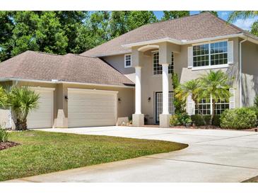 Inviting home featuring an attached three-car garage, large windows, decorative columns and manicured landscaping at 305 Country Circle E Dr, Port Orange, FL 32128