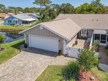 Charming home featuring an attached garage and an inviting brick-paved driveway, located near a serene pond at 42 Fore Dr, New Smyrna Beach, FL 32168