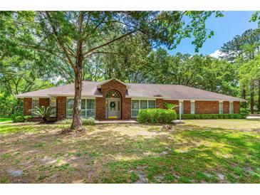 Charming brick single-story home with a well-manicured lawn and mature trees providing ample shade at 32030 Dewberry Ln, Sorrento, FL 32776