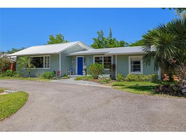 Charming single story home with a metal roof, lush landscaping and a large driveway at 913 Palmetto St, New Smyrna Beach, FL 32168