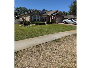 Charming single-story home boasts a well-manicured lawn, stone accents, and a two-car garage, offering curb appeal at 115 Los Arbor Dr, Deland, FL 32724
