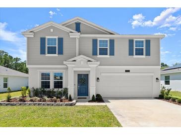 Charming two-story home featuring blue shutters, a manicured lawn, and a two-car garage at 2516 Hoptree Ln, Edgewater, FL 32141