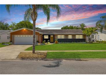 Charming single-story home with a well-manicured lawn and a colorful sunset backdrop at 2548 E Compton St, Orlando, FL 32806